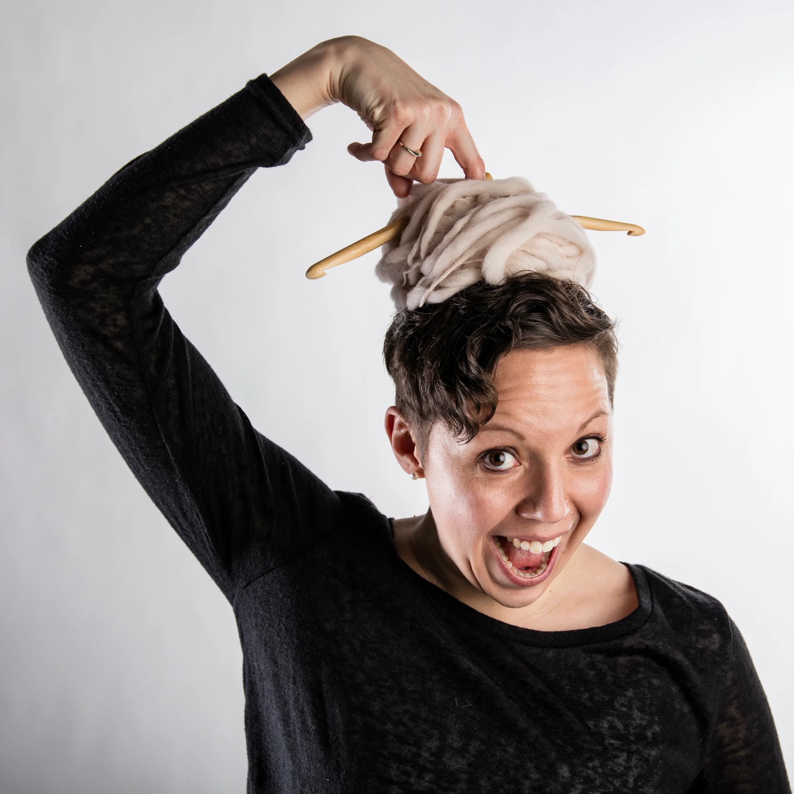 A photo of crochet designer Michaela Schönauer with a ball of yarn on her head.