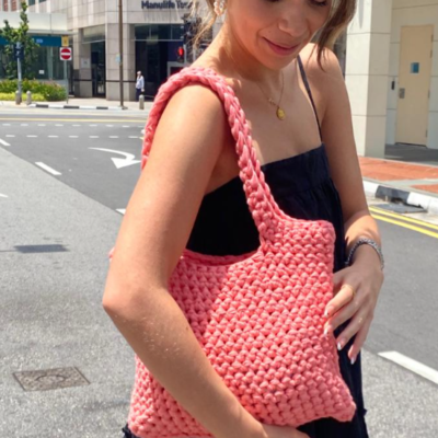 Photo of a woman carrying a peach colored crochet handbag